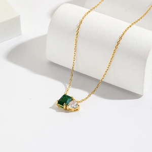 18K gold plated necklace with emerald rectangle and heart cubic zirconia on white stand