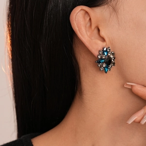 Close-up of vintage flower earrings with blue rhinestones on a model's ear