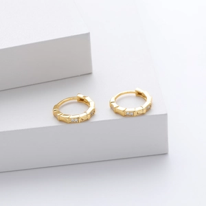 Close-up of gold bamboo-style sterling silver earrings with zircons on white steps