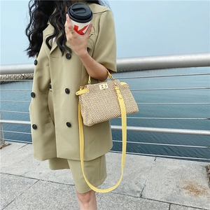 Detail of the woven straw beach bag with yellow leather trim and gold twist lock closure