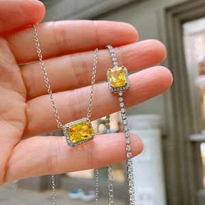 Detail of silver jewelry set with yellow radiant cut halo pendant and bracelet