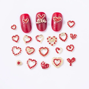 Détail macro de strass pour ongles en forme de cœur rouge avec base dorée élégante