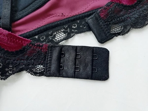 Détail d'un soutien-gorge en velours bordeaux avec dentelle noire et agrafage triple