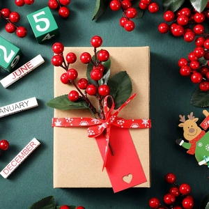 Mini confezione regalo di Natale con bacche rosse e targhetta a cuore su sfondo verde scuro