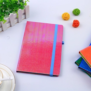 Dettaglio del taccuino iridescente rosa e viola con elastico blu di chiusura