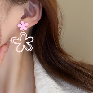 Close-up of pink layered flower earrings on a model showing the hollow floral design