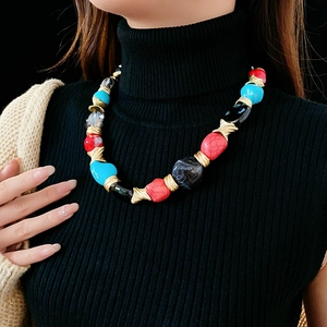 Detail of vintage necklace with irregular red blue beads and gold metal links on model