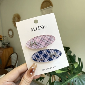 Pink and blue plaid hair clips with silver bows set on display card in a hand