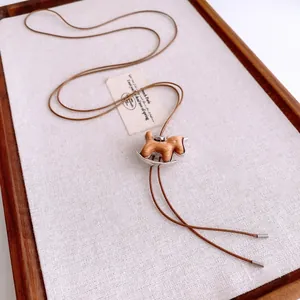 Détail du pendentif cheval à bascule en bois avec base en métal sur cordon marron