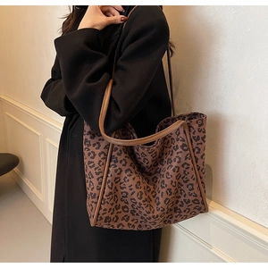 Detail of leopard print tote bag with brown straps styled with a black autumn coat