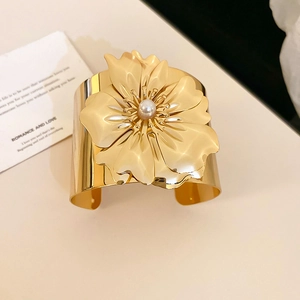 Detailed macro shot of a golden flower cuff bracelet featuring a large petal and pearl core