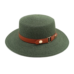 Detail of dark green straw boater hat featuring a brown leather band and gold buckle