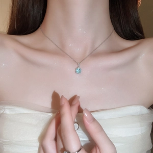 Close-up of a silver necklace with a square sea blue gemstone pendant on a model neck