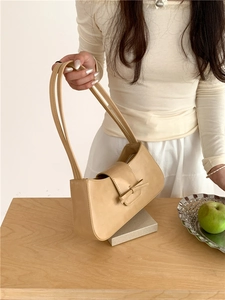 Close-up of a beige baguette bag with a decorative leather bow knot detail