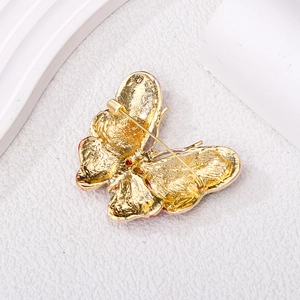 Elegant gold butterfly brooch with red crystal accents showing the secure back pin detail