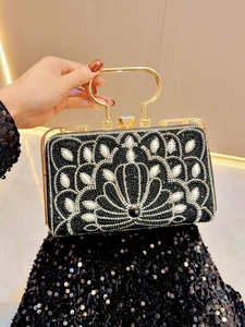 Close-up of radiant peacock pattern with pearls and crystals on black evening bag