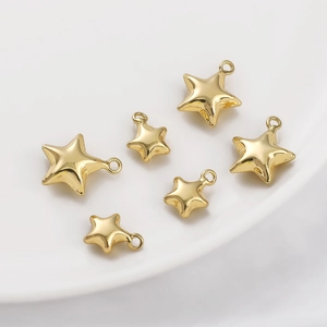 Detailed view of six 14K gold-filled star pendants in various sizes on a white plate