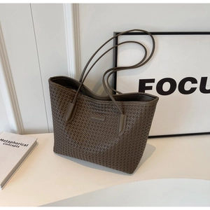 Detail of a brown checkered woven tote bag showing the fine PU leather craftsmanship