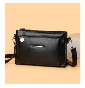 Detail view of black soft PU leather crossbody bag featuring multiple zippers and metal trim
