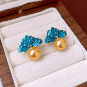 Detail of vintage flower earrings with blue-green enamel and golden pearls on velvet