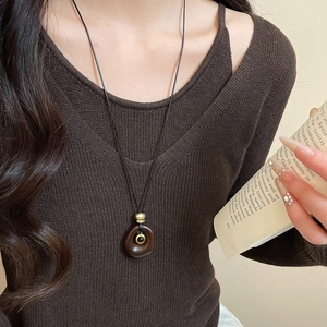 Detail of vintage resin tiger eye oval pendant necklace on a brown knit sweater