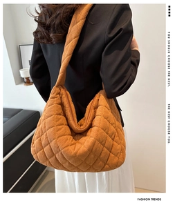 Detailed view of the brown quilted corduroy tote bag worn by a model in a minimal room