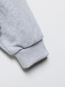 Gros plan des poignets en tricot côtelé gris d'un ensemble de survêtement brodé