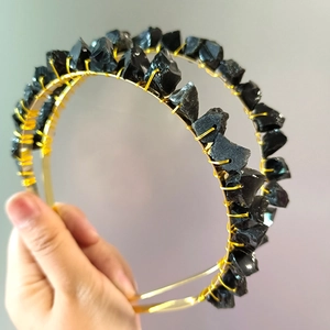 Detail of handmade gold wire-wrapped black raw stone hoop earrings for women