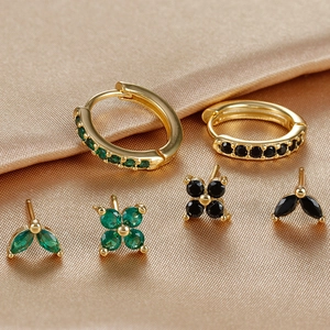 Detailed macro view of S925 silver needle gold earrings set with green and black zircons