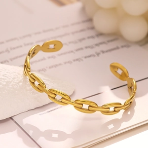 Detailed shot of a gold-plated C-shaped chunky chain link cuff on a neutral background