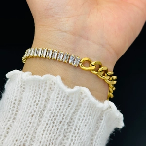 Elegant gold chain bracelet with rectangular zircon stones worn over white lace cuff
