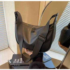 Detail of adjustable strap and zipper closure on a black nylon crescent shoulder bag