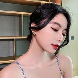 Detailed view of elegant gold pearl earring with leaf-shaped zirconia on model's ear