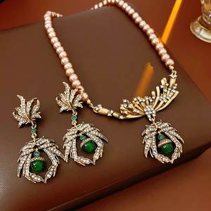 Macro shot of vintage leaf earrings and pearl necklace with green gemstones on leather