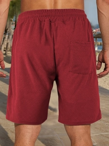 Detailed back view of men's red jacquard casual shorts on a sunny beach setting