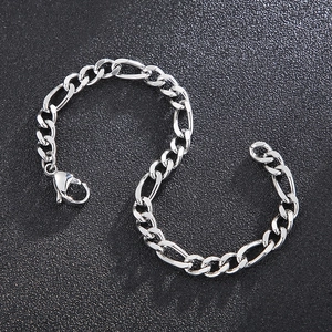 Detailansicht eines silbernen Figaro-Armbands mit Karabinerverschluss auf dunklem Grund