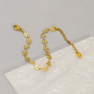 Detail of gold flower link bracelet with blue centers and s.steel hallmark charm