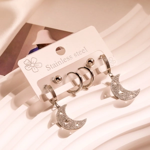 Set of stainless steel earrings featuring moon pendants and studs on a display card