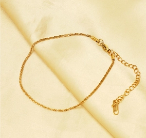 Detail shot of golden anklet with lobster clasp and extension chain on silk background