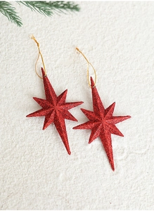 Macro shot of two red glittery octagonal star ornaments with gold strings on pine needles