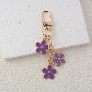Macro shot of three purple enamel flower pendants on a gold-plated metal keychain