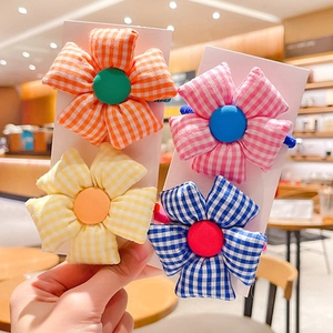 Detail of four colorful floral fabric hair ties with grid patterns and button centers