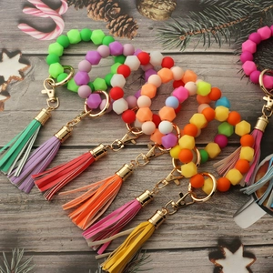 Colorful silicone bead keychains with PU tassels and lobster clasps on a rustic wood background