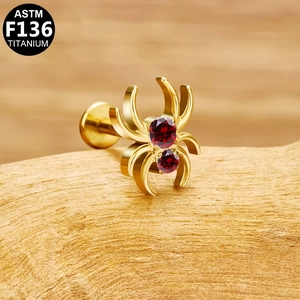 Macro d'un piercing labret araignée en titane F136 avec des zircons rouges brillants