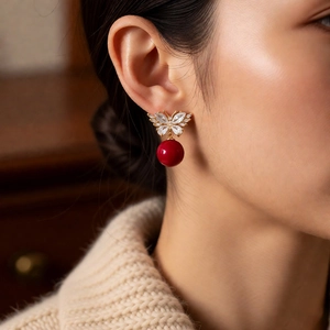 Close-up of elegant bow butterfly earrings with red pearls and zircon on model