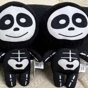 Detail view of two cartoon skeleton plush dolls with white heart chest pattern and tags