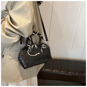 Detail view of black crocodile pattern handbag featuring a unique snake-shaped metal handle