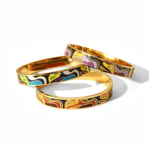 Macro detail of three colorful enamel bangle sets with golden frames and abstract patterns