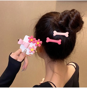 Detailed view of pink resin flower and bone-shaped hair clips styled on hair