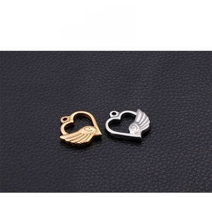 Detailed view of hollow heart and feather wing charms in gold and silver finishes